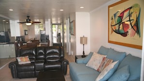 A living room with a black leather sofa, a blue sofa, and a dark wooden coffee table. - Sunset Getaway (Oceanside)