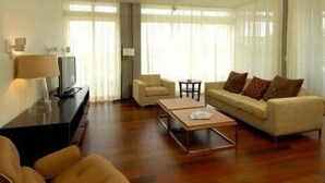 A modern living room with a sofa, armchairs, a coffee table, and a TV. - Turtle Glass 309 (Port St. Joe)