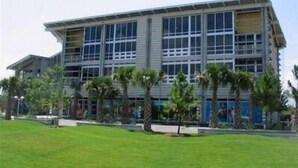 A multi-story building with a flat roof, large windows, and a grassy area in front. - Turtle Glass 309 (Port St. Joe)