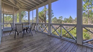 A covered outdoor area with a wooden deck, metal-framed windows, and a table with chairs.