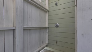 A narrow wooden deck with a metal door and a small step leading to a raised platform.