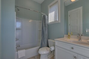 A bathroom with a bathtub, toilet, and sink. - Holliday House (Port St. Joe)