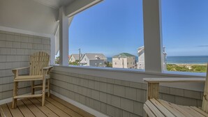 A wooden deck with two Adirondack chairs, a view of houses and the ocean. - Cape Cottage (Port St. Joe)