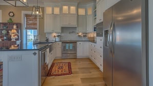 A modern kitchen with white cabinets, a stainless steel refrigerator, and a built-in oven. - Cape Cottage (Port St. Joe)
