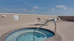 A rooftop pool area with a clear blue sky, lounge chairs, and a pool with a metal ladder. - Sunset Palms (Port St. Joe)