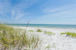 A beach with white sand and sparse grass. - Sunset Palms (Port St. Joe)