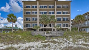 A multi-story hotel with balconies, a covered entrance, and palm trees. - Sunset Palms (Port St. Joe)