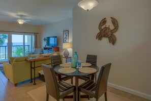 A living room with a dining area, a television, and a balcony with a view. - Sunset Palms (Port St. Joe)