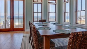 A dining area with a wooden table, woven chairs, and large windows with ocean views. - Sea Section (Port St. Joe)