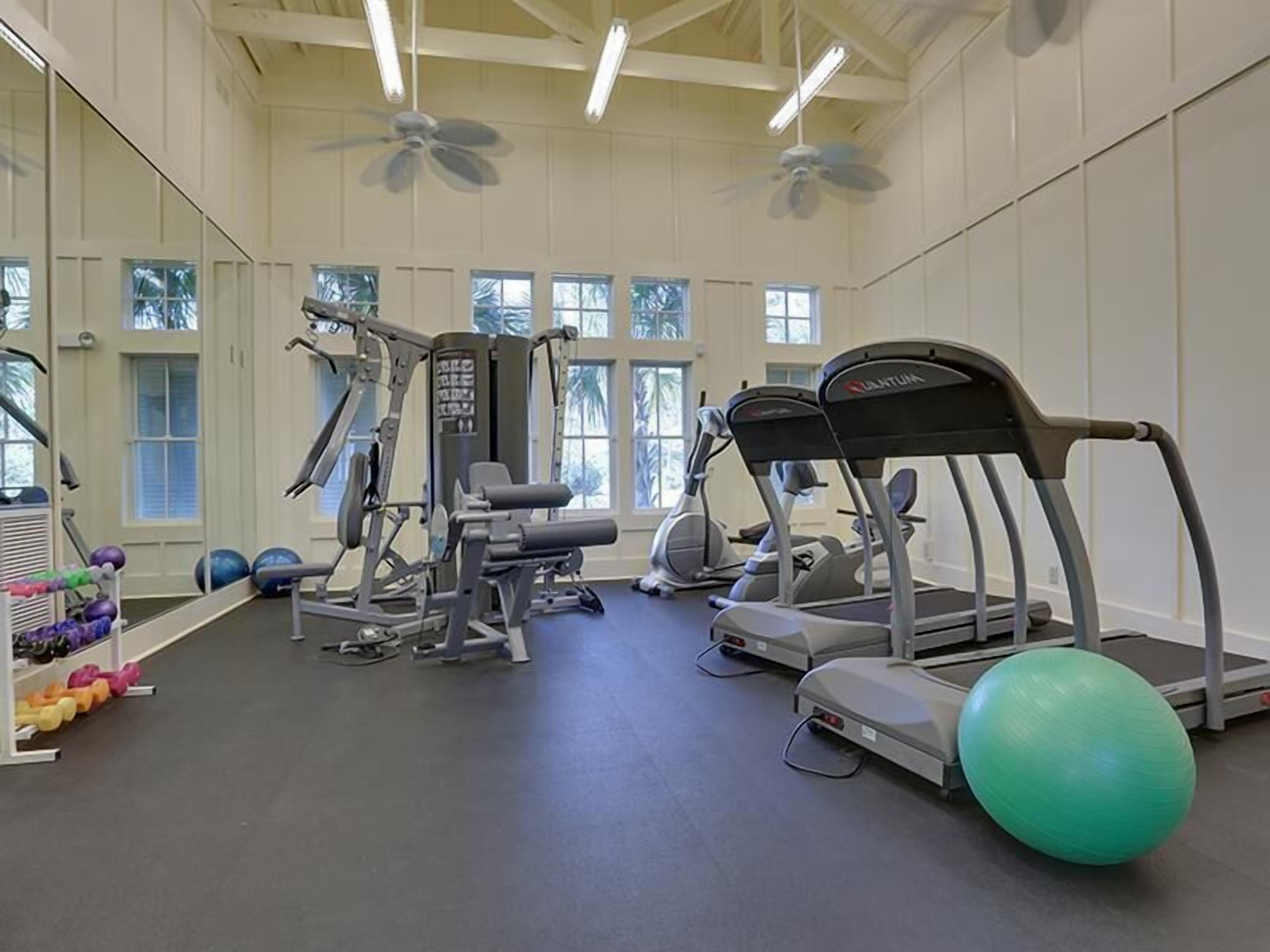 A gym with treadmills, elliptical machines, free weights, and exercise balls.