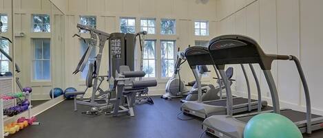 A gym with treadmills, elliptical machines, free weights, and exercise balls.