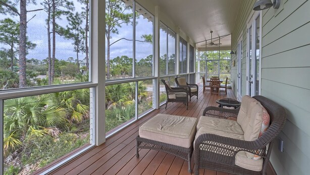 A covered porch with wicker furniture, a table, and chairs. - Sunset Cottage (Port St. Joe)