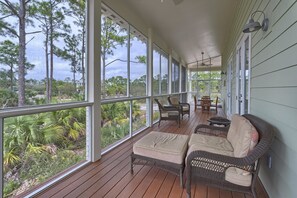 A covered porch with wicker furniture, a table, and chairs. - Sunset Cottage (Port St. Joe)