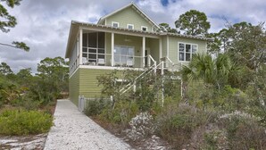 A two-story house with a covered porch and a pathway leading to the entrance. - Sunset Cottage (Port St. Joe)