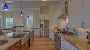 A modern kitchen with white cabinets, stainless steel appliances, and a wooden floor.