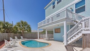 Une maison à deux étages avec une piscine, du mobilier d’extérieur et une terrasse en bois.