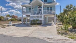 Une maison à deux étages située en bord de mer, dotée d’un balcon, d’un garage et d’un jardin paysager à l’avant.