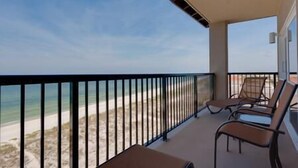 Un balcó amb vista a la platja, equipat amb dues gandules i una taula petita.
