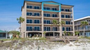 A multi-story hotel with balconies, a covered entrance, and a sandy beach in the foreground. - 4 Better Vues (Port St. Joe)