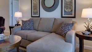 A living room with a beige sectional sofa, two side tables with lamps, and framed artwork on the wall. - 4 Better Vues (Port St. Joe)