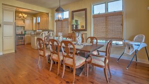 A spacious kitchen with wooden cabinets, a dining table with chairs, and a baby high chair. - Maui Escape (Port St. Joe)