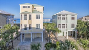 A multi-story building with a flat roof and a balcony, surrounded by palm trees and a clear blue sky. - Maui Escape (Port St. Joe)
