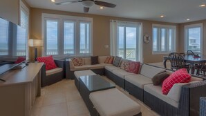 A spacious living area with a sofa set, a dining table, and a television. - Serenity Now (Port St. Joe)