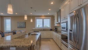 A modern kitchen with granite countertops, stainless steel appliances, and pendant lighting. - Serenity Now (Port St. Joe)