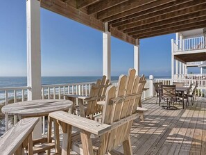 A wooden deck with Adirondack chairs and a table, overlooking the ocean. - Smiling Bob s (Port St. Joe)