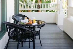 A wicker table with breakfast items on a balcony.