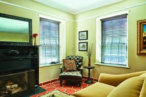 A living room with a fireplace, a large mirror, and two windows with blinds.