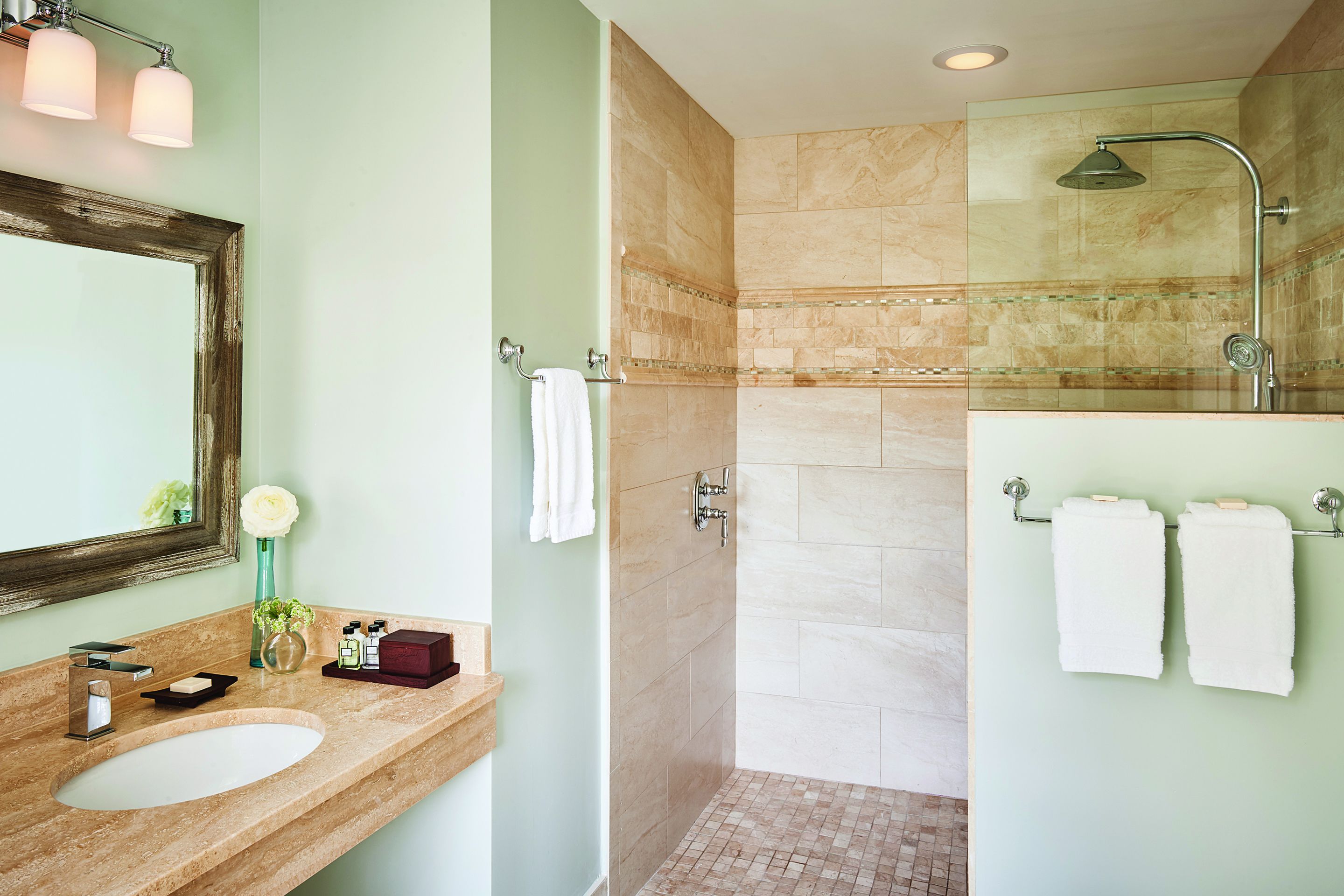 A bathroom with a sink, mirror, and shower.