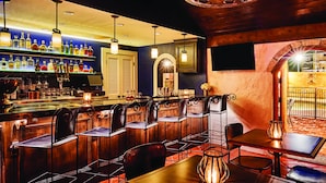 A bar area with multiple seating options, a well-stocked liquor shelf, and a warm, inviting atmosphere.