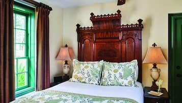 Un dormitorio con una cama grande, dos lámparas de noche, cabecera de madera y ventana verde.