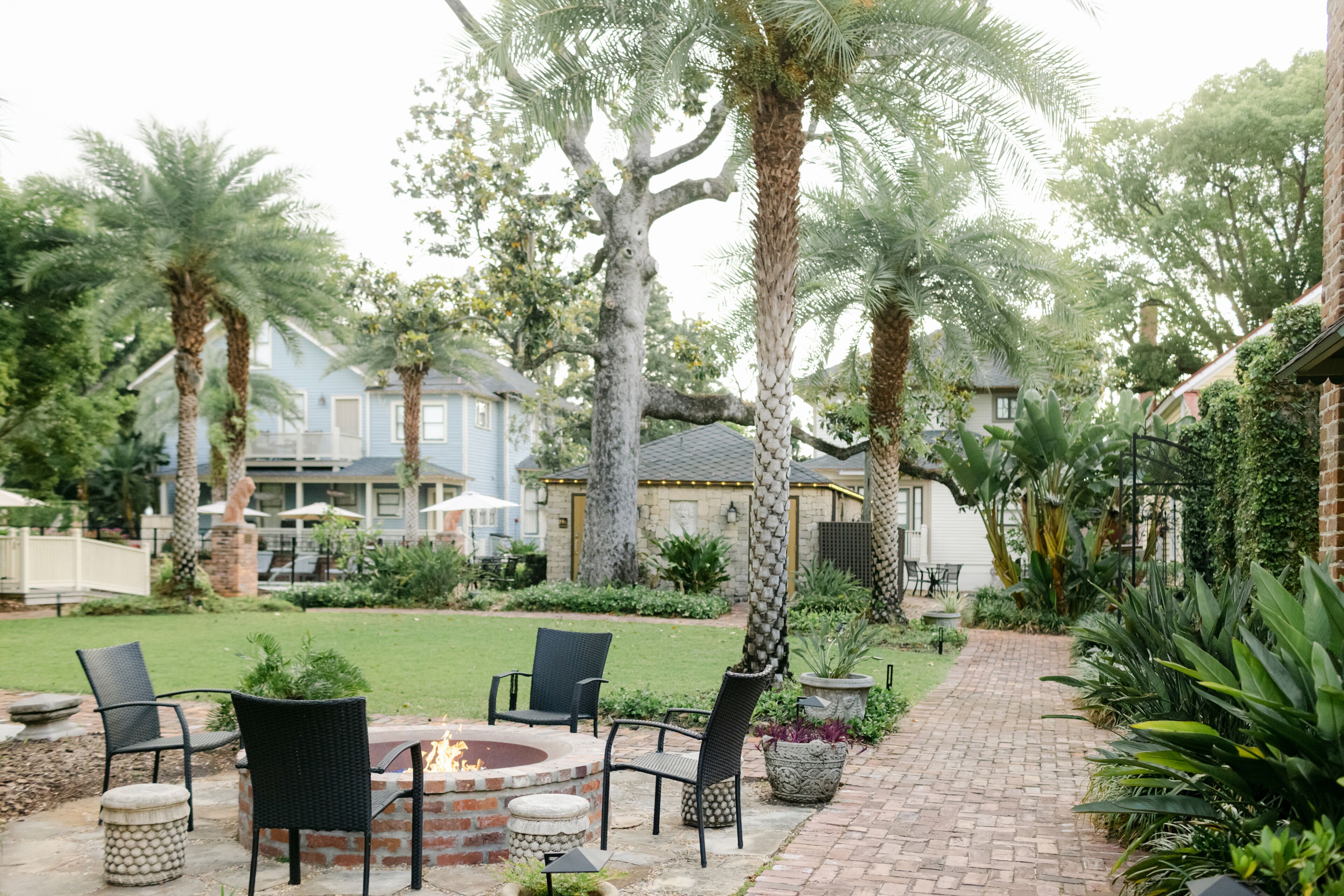 Un patio con mobiliario exterior, una zona de fogata y un camino de ladrillo.