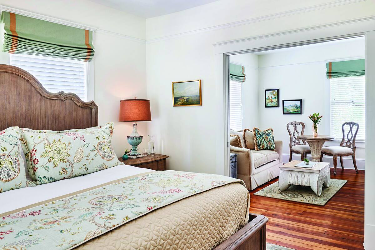 A bedroom with a bed, a nightstand, a lamp, and a window with blinds.