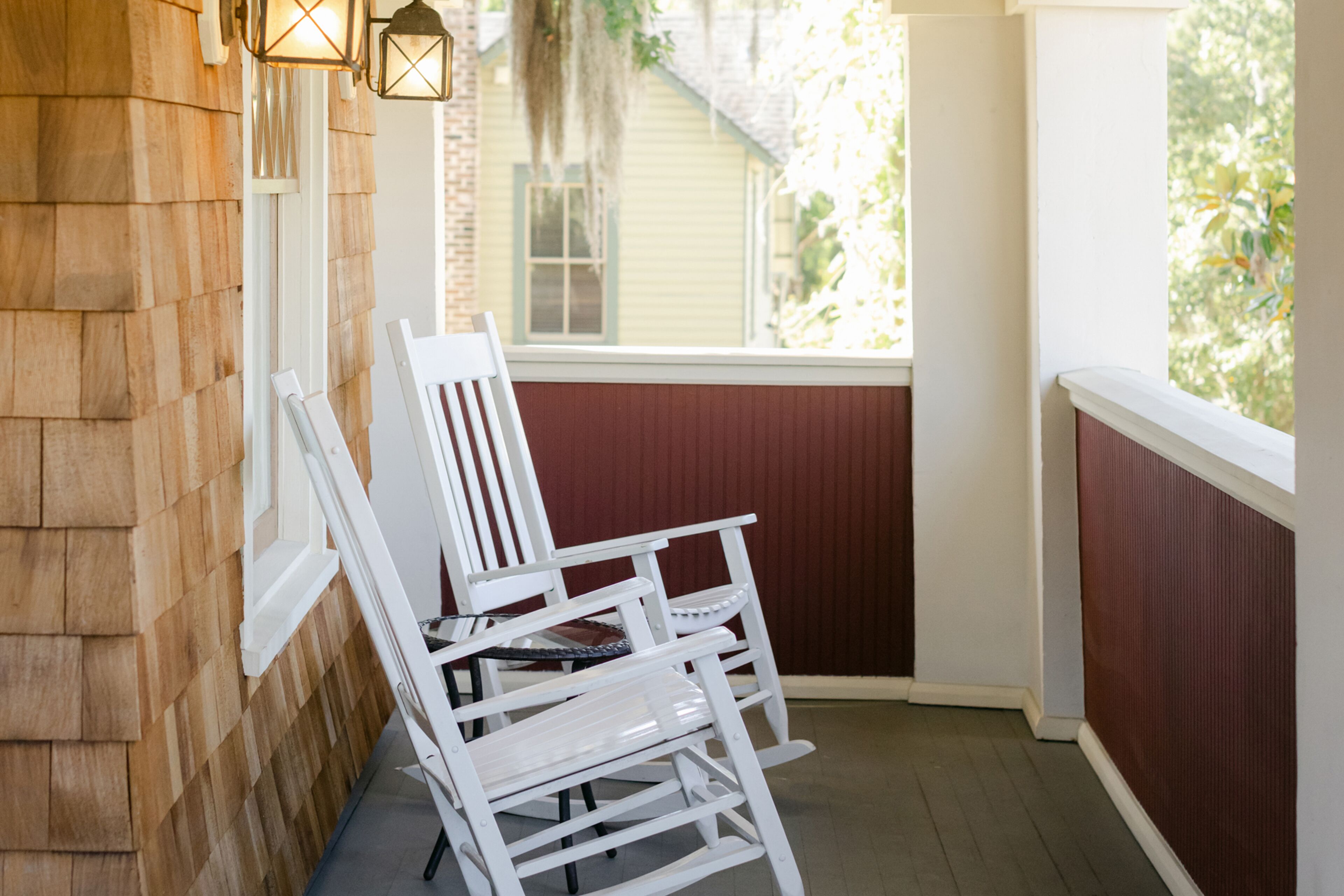 A wooden porch with a white rocking chair and a small table.