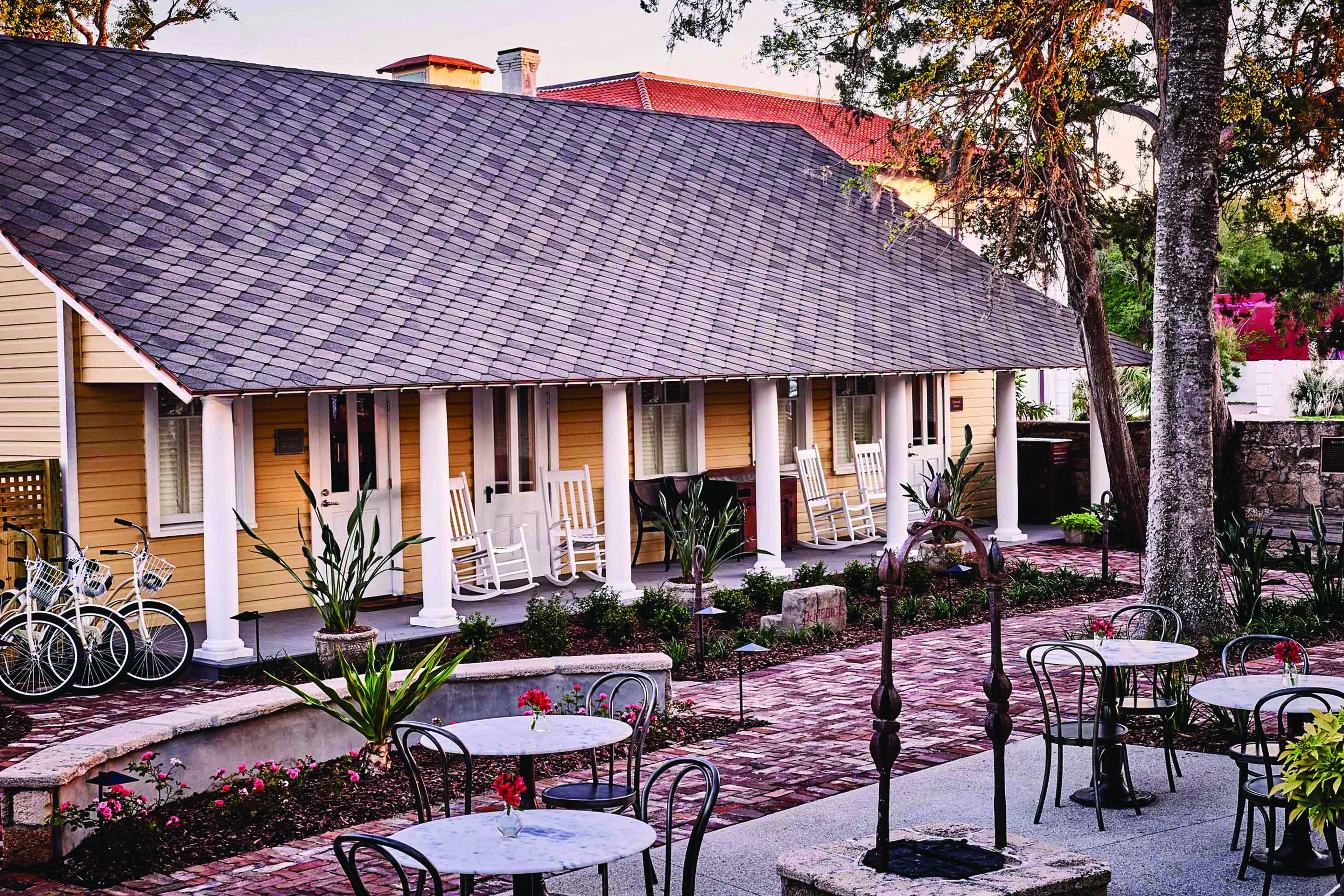 A building with a porch, outdoor seating, and bicycles.
