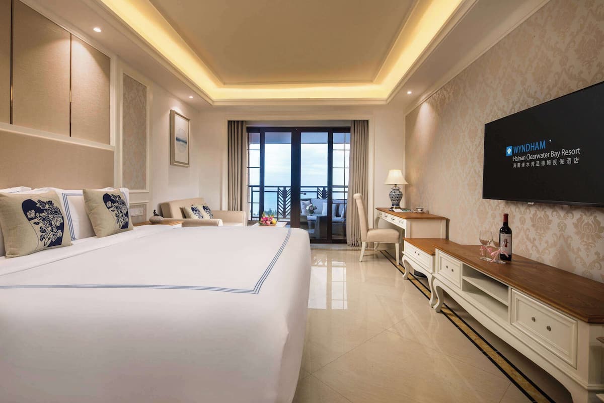 Habitación de hotel con una cama grande, televisión, escritorio y vistas al exterior.