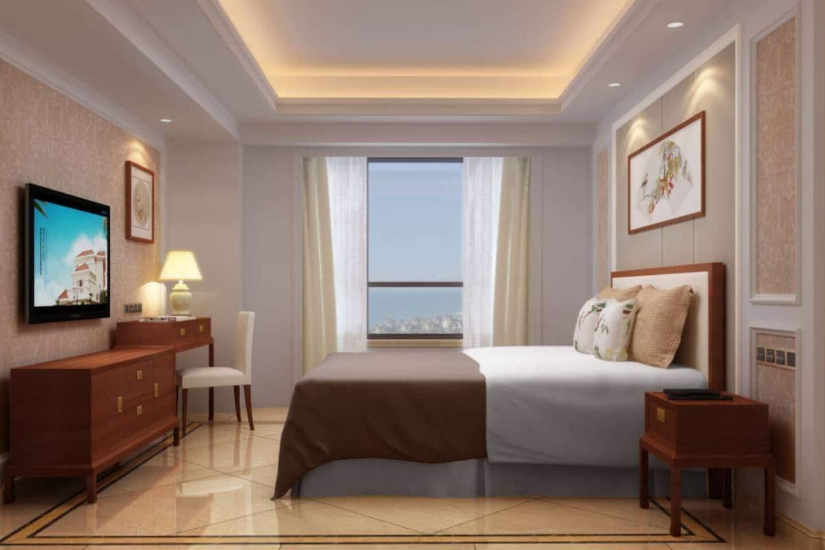 Habitación de hotel con cama, mesitas de noche, televisor y vistas a la ciudad.