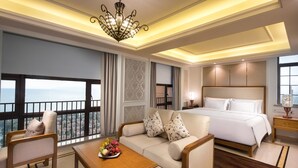 A hotel room with a balcony, a bed, a sofa, a coffee table, and a nightstand. - Wyndham Hainan Clearwater Bay Resort (Lingshui)