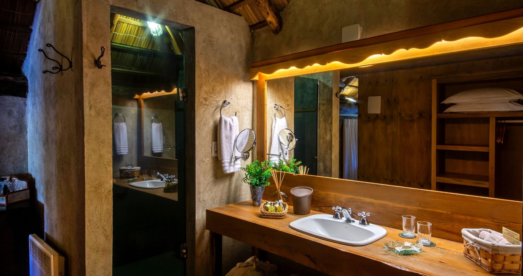 A wooden bathroom with a large mirror, two sinks, and a wooden vanity.