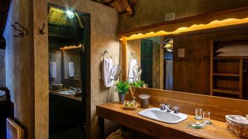 A wooden bathroom with a large mirror, two sinks, and a wooden vanity.