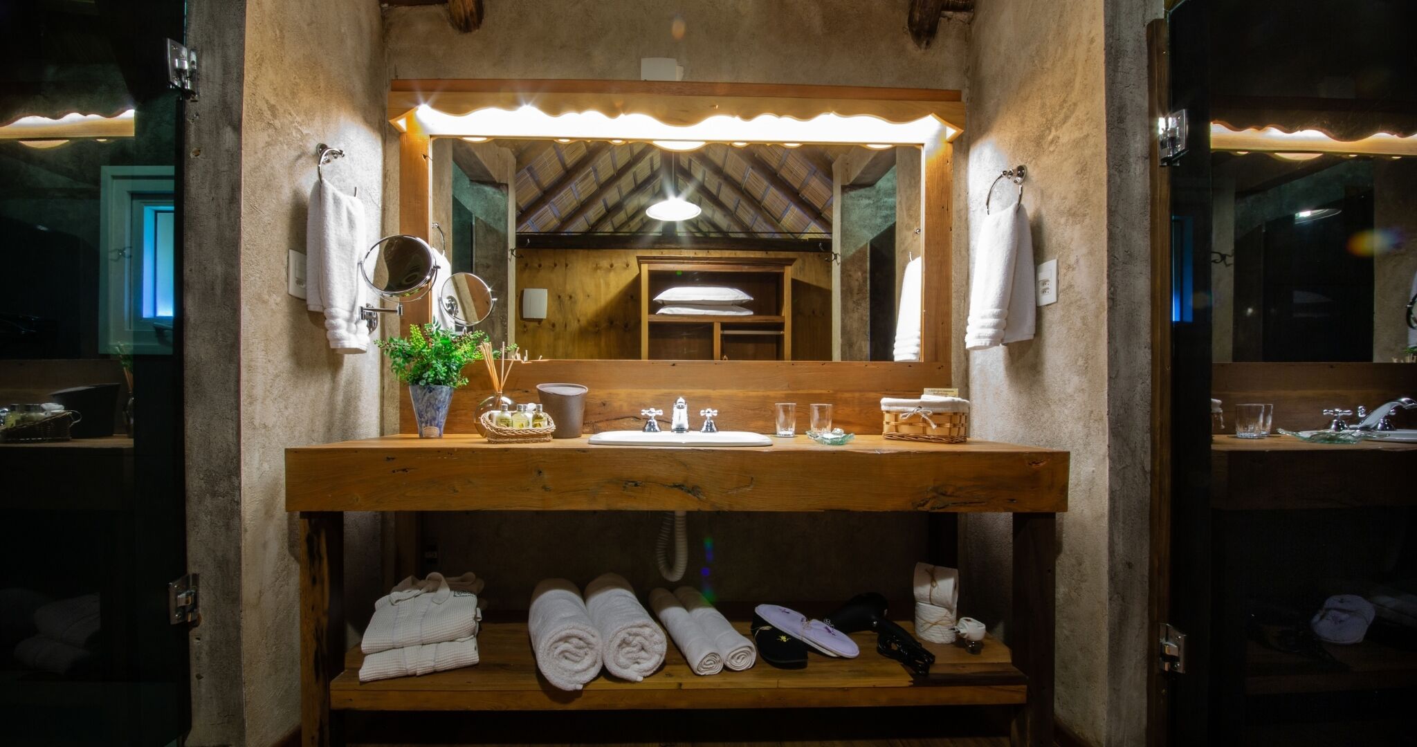 A wooden vanity with a mirror, sink, and towel storage.