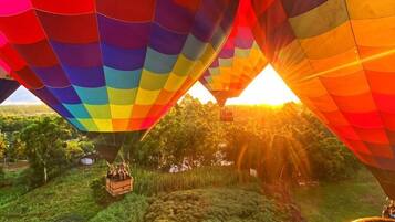 Eine Heißluftballon mit Regenbogenmuster über einer üppigen Landschaft.