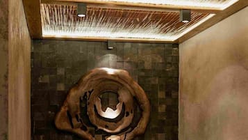 Relax in a contemporary bathroom with a bathtub, unique circular sculpture, and mosaic tile walls.