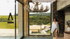 A modern interior with a large glass door leading to a pool, a unique antler chandelier, and a view of a lush landscape. - Parador Cambará do Sul (Cambara do Sul)