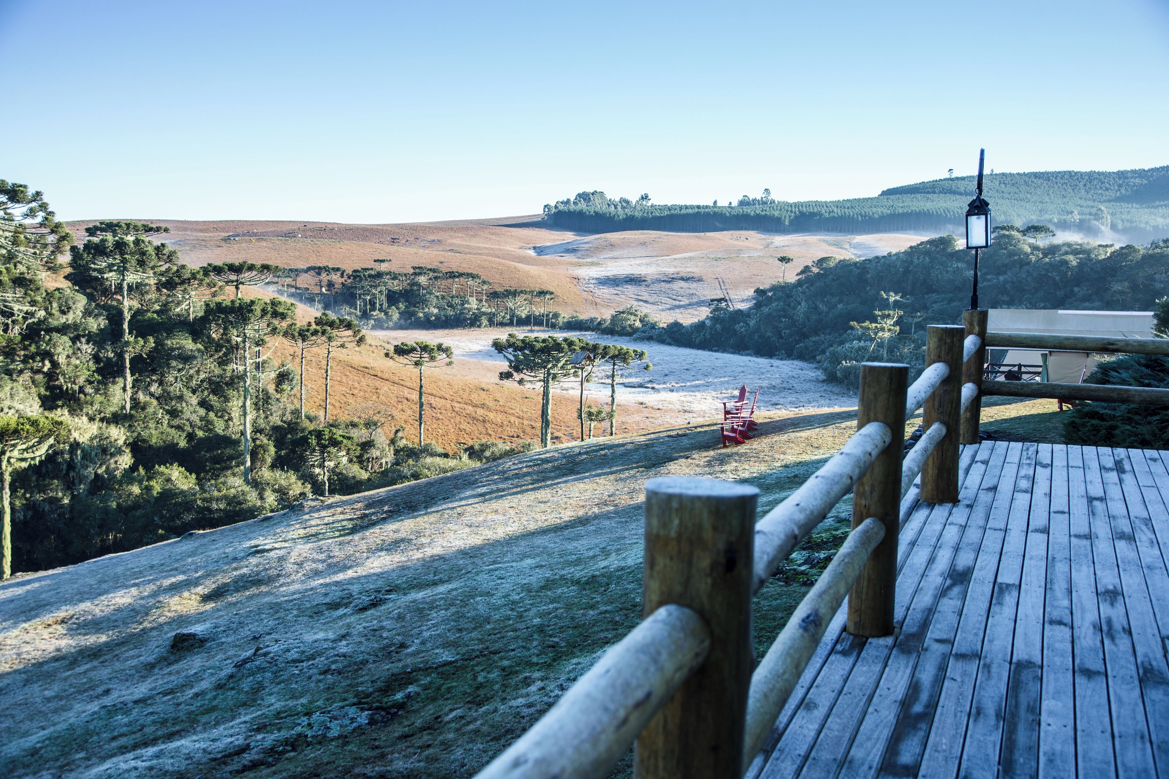 Un pontile in legno con vista su una valle e colline lontane.