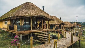 A series of thatched-roof cottages with wooden decks and a wooden walkway connecting them. - Parador Cambará do Sul (Cambara do Sul)