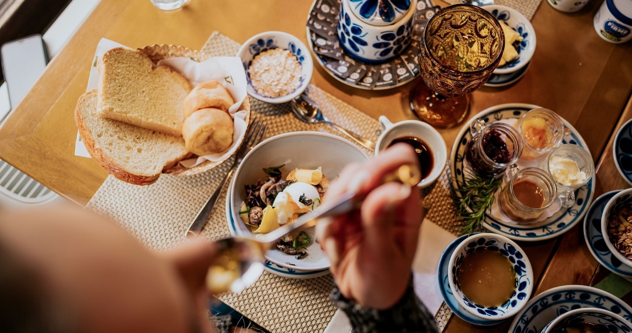 Una mesa de comedor con diversos platos, como pan, un tazón de sopa y una taza de té.